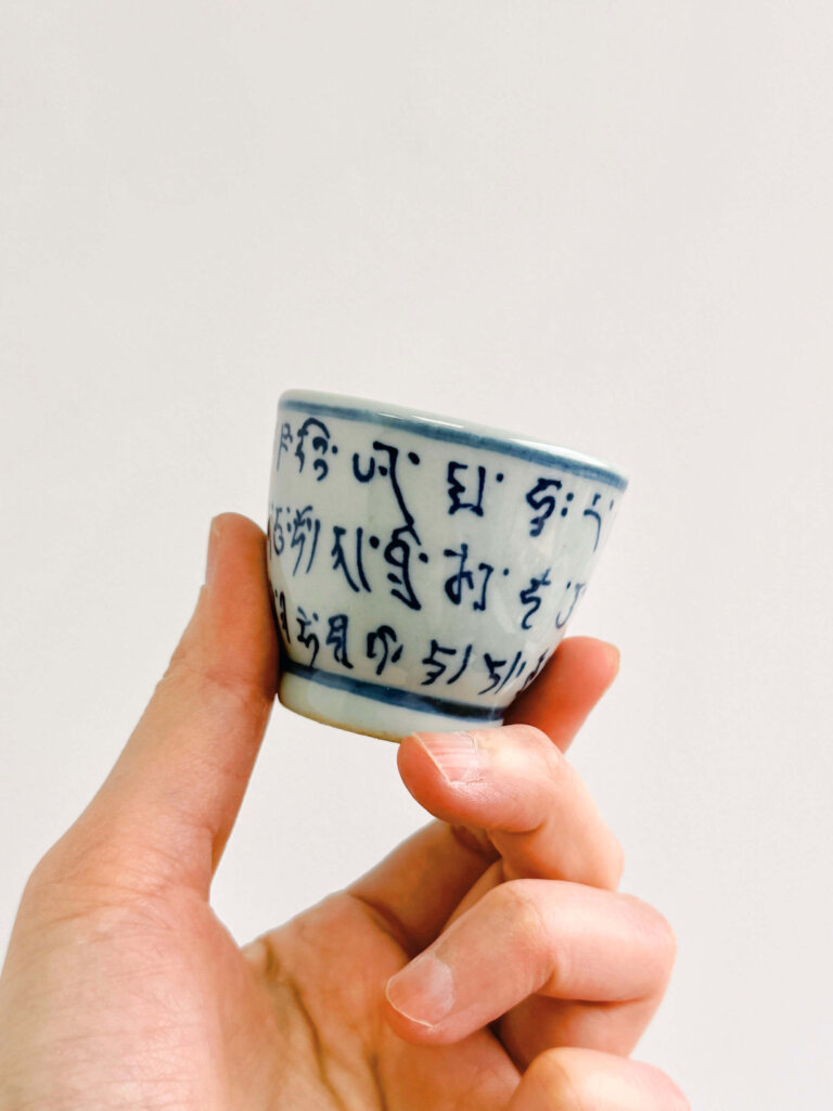 Qing Hua Ci Blue and White Porcelain teacup hand painted with Sanskrit Script - hand holding (mini size)