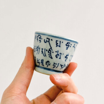 Qing Hua Ci Blue and White Porcelain teacup hand painted with Sanskrit Script - hand holding (mini size)